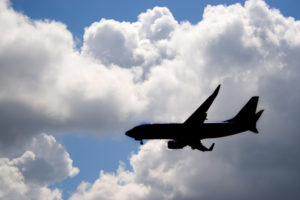 A silhouette of a commercial passenger plane over a blue sky in its descent to land.
